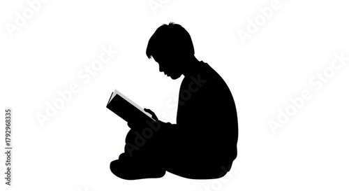 Silhouette of a boy sitting and reading a book with focus and concentration on the story in the book