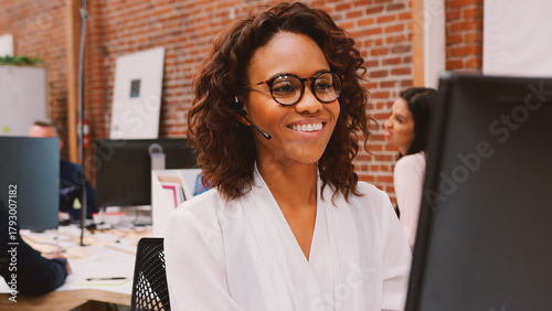 Female Customer Services Agent Working At Desk In Call Center