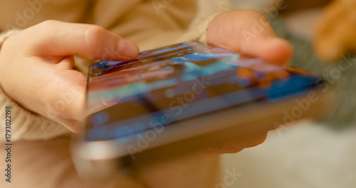 Female professional scrolling through social media content, navigating digital platform with focused thumb movements while sitting comfortably at home
