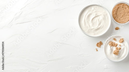 Creamy yogurt in bowls with brown sugar crumbs on a white textured surface.