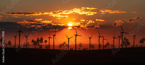 Wind turbines on the horizon during sunset, landscape with trees and shrubs. Energy, environment, wind power, sustainable energy.
