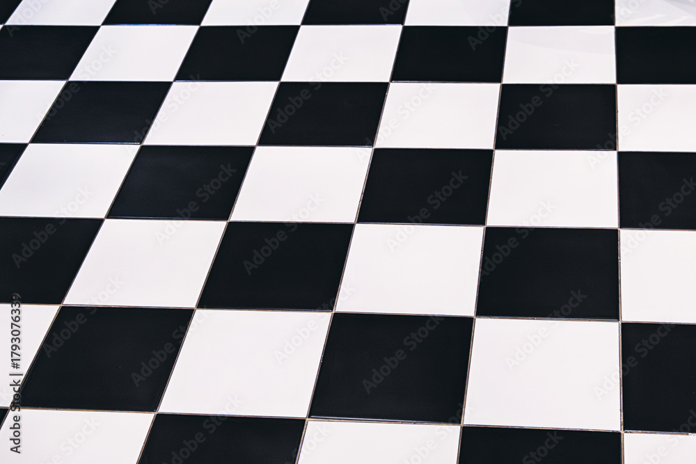 Fototapeta premium Checkered floor pattern with black and white tiles creating a geometric, abstract background with strong perspective
