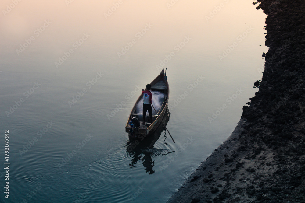Naklejka premium A Wooden Canoe Floating on Still Water Near a Dark Shoreline
