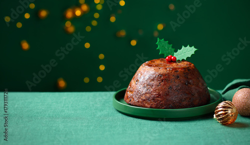 Christmas pudding, fruit cake. Traditional festive dessert. Green background with lights garland. Close up. Copy space.