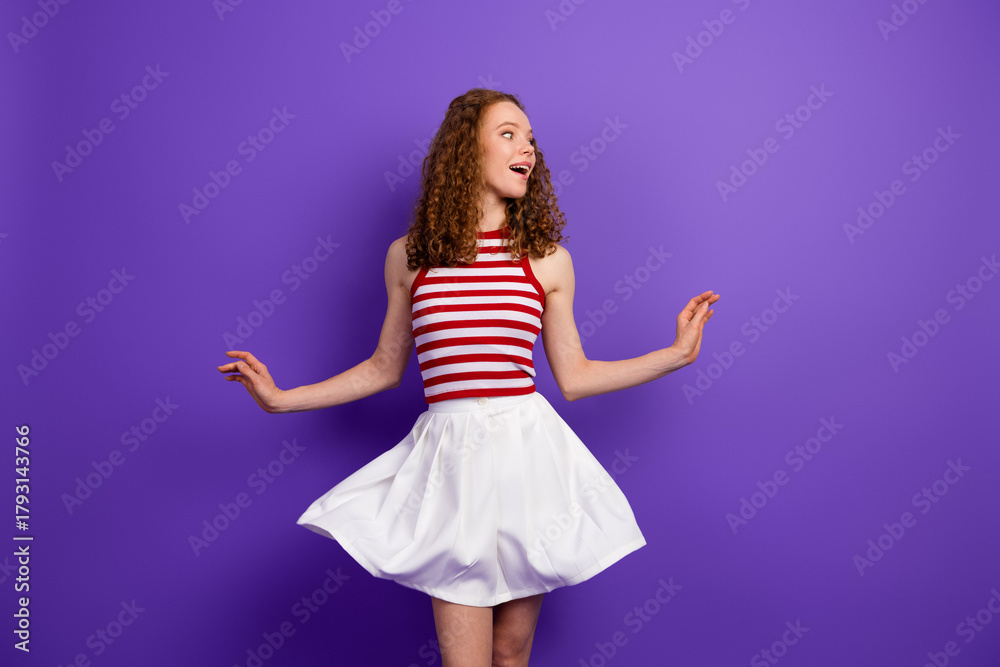 Naklejka premium Young woman in striped singlet and white skirt spins with joy against purple background fashion model style and summer vibe