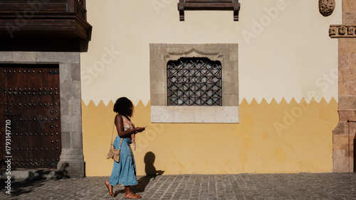 Woman walking on cobblestone street using phone