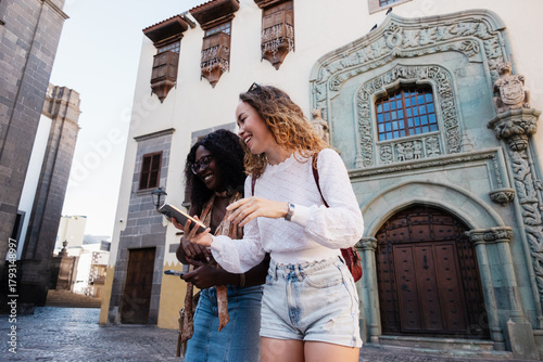 Diverse women friends exploring city using smartphone location app