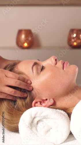 caucasian woman receiving head massage in tranquil spa setting with rolled towel under neck, warm candlelight glow, professional therapist using gentle scalp strokes, massage in spa center, vertical