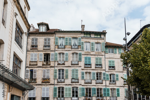Charming white buildings with green shutters in the heart of Bayonne, France.
