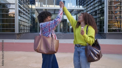 African American women friends laughing and eating ice cream outdoors
