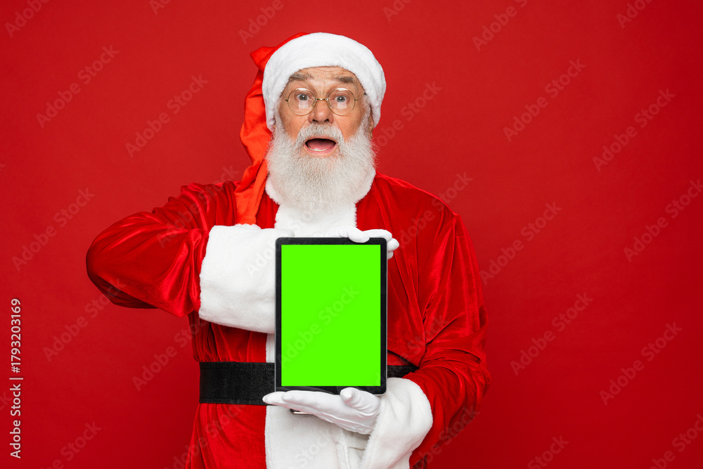 Naklejka premium Discount, marketing, sales, advertisement, presents, gifts selling concept. Holly jolly x mas, noel is soon! Santa Claus holding using showing demonstrate mock up blank screen isolated red background