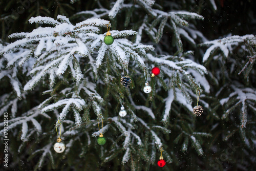 Snow covered fir branches with Christmas decorations on winter outdoor