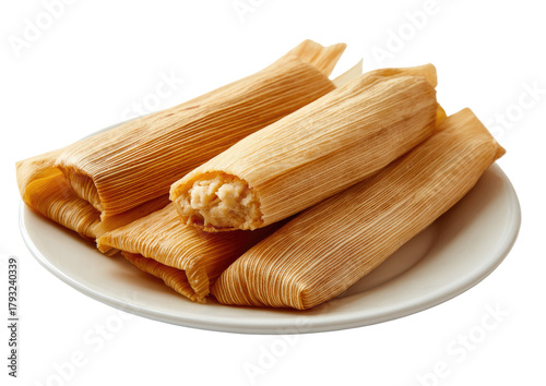 Golden tamales rest on a white plate