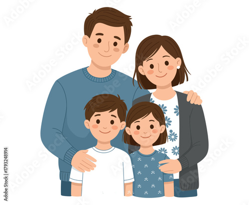 A happy family of four with parents and two children stands together embracing.