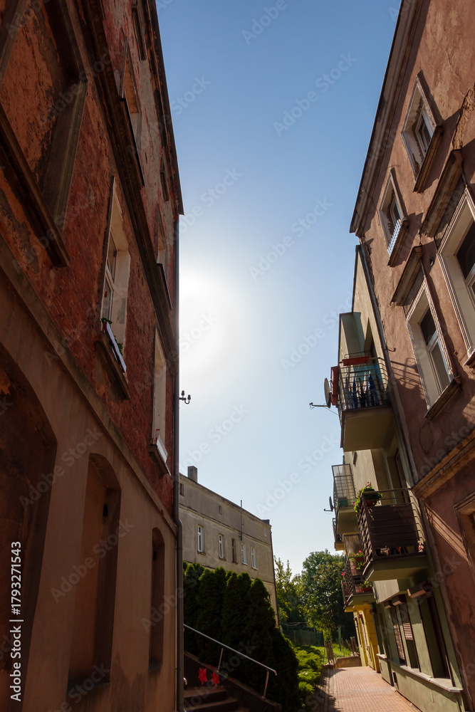 Obraz premium Historic Tenement Houses in Gniezno, Poland - Charming Street Scene Ideal for Travel Agencies, City Guides, and Tourism Campaigns. Narrow Street with Old Brick Buildings and Warm Afternoon Sunligh