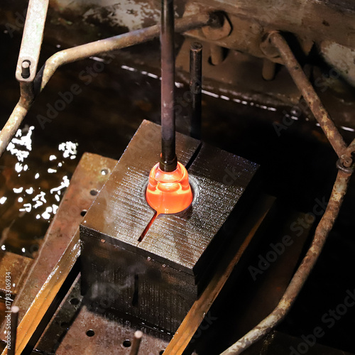 A glass crafter is burning and blowing an art piece.