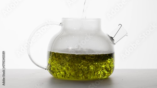 Pouring herbal tea into transparent  teapot