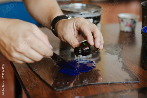 Bild auf Leinwand Hands diluting blue oil lithographic printing ink with oil on a glass slab, prep