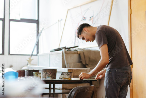 Young art student focusing on creating artwork in a bright studio, developing his skills and expressing creativity
