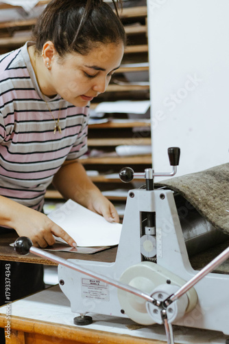 Art student working with printmaking press, focusing on artistic craft and creating an engraving