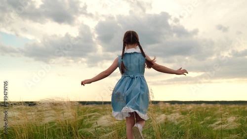 Baby girl playing superhero in nature. kid girl run in park. Happy little girl in dress running with raised hands on grass meadow. Children's dreams. Cheerful little girl play running in summer park