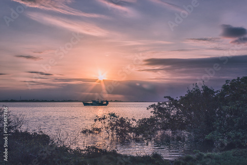 Boat silhouette at sunset over calm water