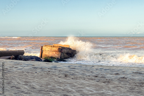 Wave crashing on concrete ruins at the beach