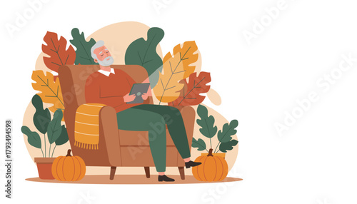 Elderly man using tablet in a cozy armchair enjoying autumn leisure time at home