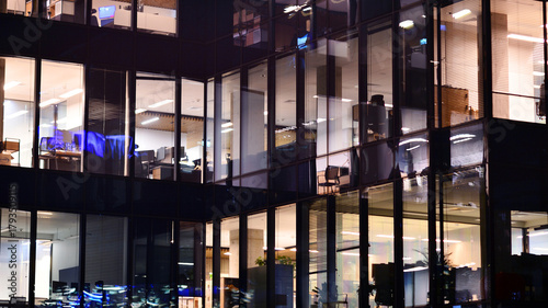 Modern office building in city center illuminated at night. Rows of lit windows against the architectural grid of a modern facade.