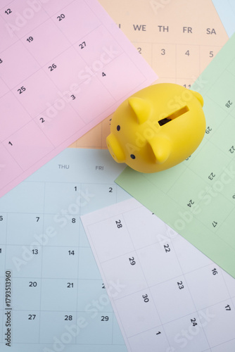 Long-term financial planning. Yellow piggy bank on a multi-colored calendar spread