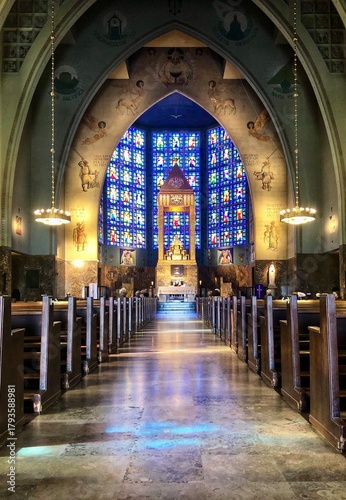 Fotografia Interior of Our Lady of the Rosary of Fatima Church in Lisbon, with symmetrical nave, illuminated altar, and colorful stained-glass windows
