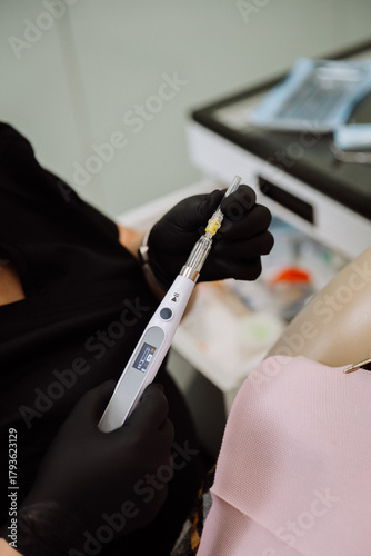 Computerized dental anesthesia injector in gloved hands during patient procedure