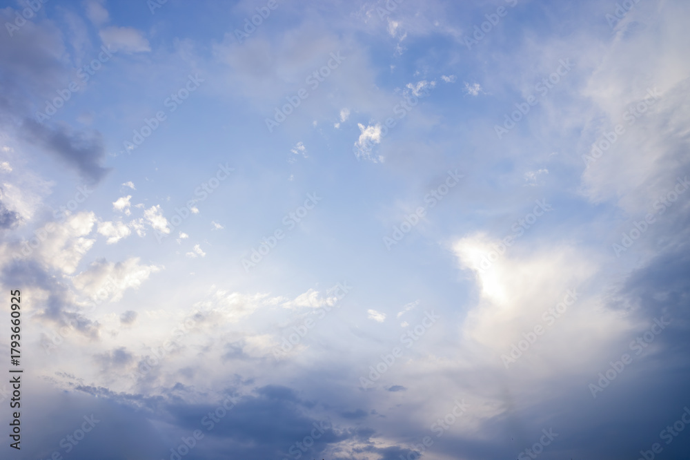 Fototapeta premium Vast blue sky presenting fluffy white and dark grey cumulus clouds, creating a bright opening in the center, symbolizing hope, clarity, and changing weather conditions in nature