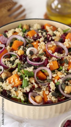 Pouring homemade dressing on top of roasted pumpkin quinoa arugula chickpea salad. Vertical video. Close-up.