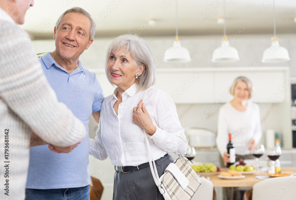Fototapeta premium Two elderly couples meet for a holiday dinner at home. Greet each other