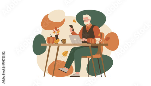 Senior man works remotely on laptop and phone at an autumndecorated desk