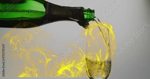 Tilting green bottle pouring pale champagne into flute, yellow swirls rising, filling glass