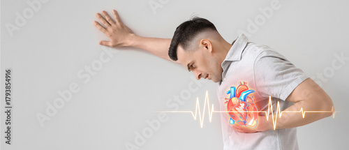 Young man having heart attack on light background