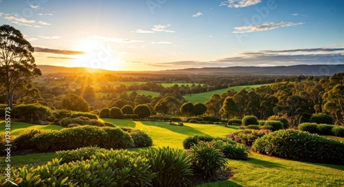 Lush green hillside gardens and fields, bathed in golden sunset light, framed by trees