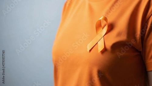 Animated close-up of a hand attaching an orange awareness ribbon to an orange t-shirt.