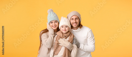 Happy family in winter clothes on color background