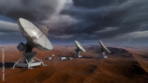 Multiple large satellite dishes in a desolate, reddish desert landscape under a dark, cloudy sky, suggesting remote communication or scientific observation.