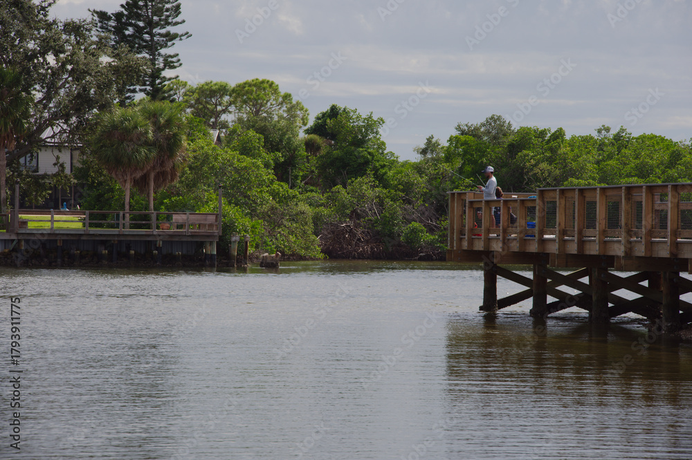 Φωτογραφία People Fishing From A Wooden Pier Over Calm Water By Lush Green Trees And Shoreline Weedon Island Park St