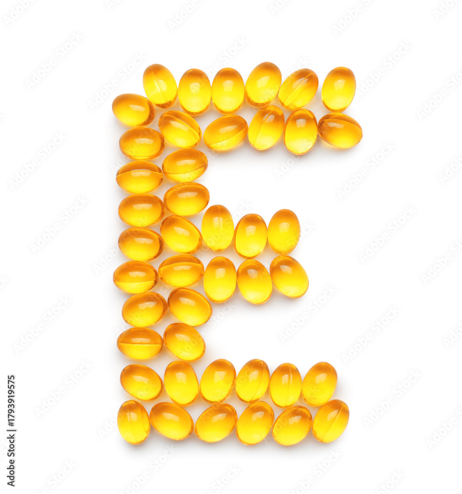 Fototapeta premium Vitamin E capsules in shape of letter on white background