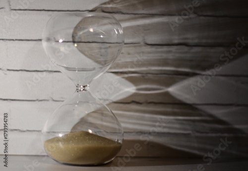 Hourglass as symbol of passing time concept photo shadow on the wall	