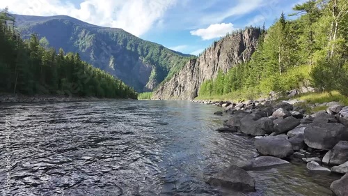 Static wide shot of a clear mountain river flowing between forested slopes and rocky cliffs — serene natural beauty perfect for cinematic backgrounds or travel documentaries.