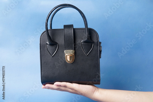 black bag is arranged in front of a solid blue backdrop