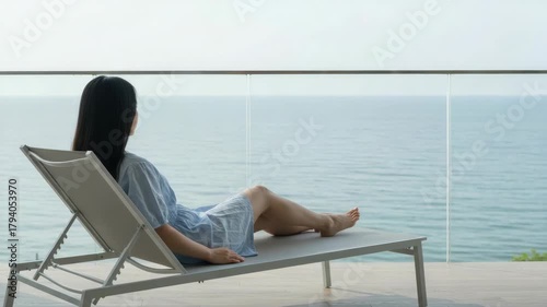 Woman relaxing on deck chair overlooking the ocean
