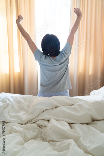 Wallpaper Mural Woman stretching in bed after wake up, back view Torontodigital.ca