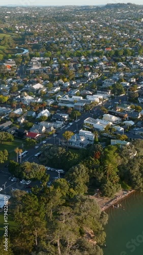 Aerial view of Point Chevalier, Auckland, New Zealand, showing a residential area bordering a park and the water. The image captures the urban landscape meeting natural elements.